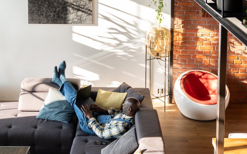 a person laying on a couch on a laptop